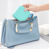 دستی که جعبه جواهرات سبز فیروزه ای رو داخل کیف آبی قرار میده