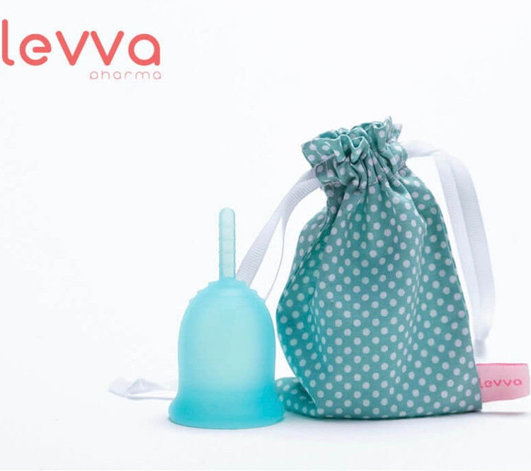 کاپ قاعدگی آبی در کنار کیسه نگهدارنده سبز رنگ